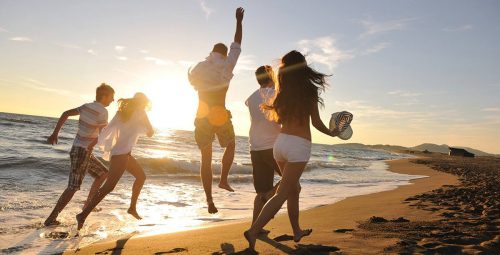 pessoas felizes pulando na praia